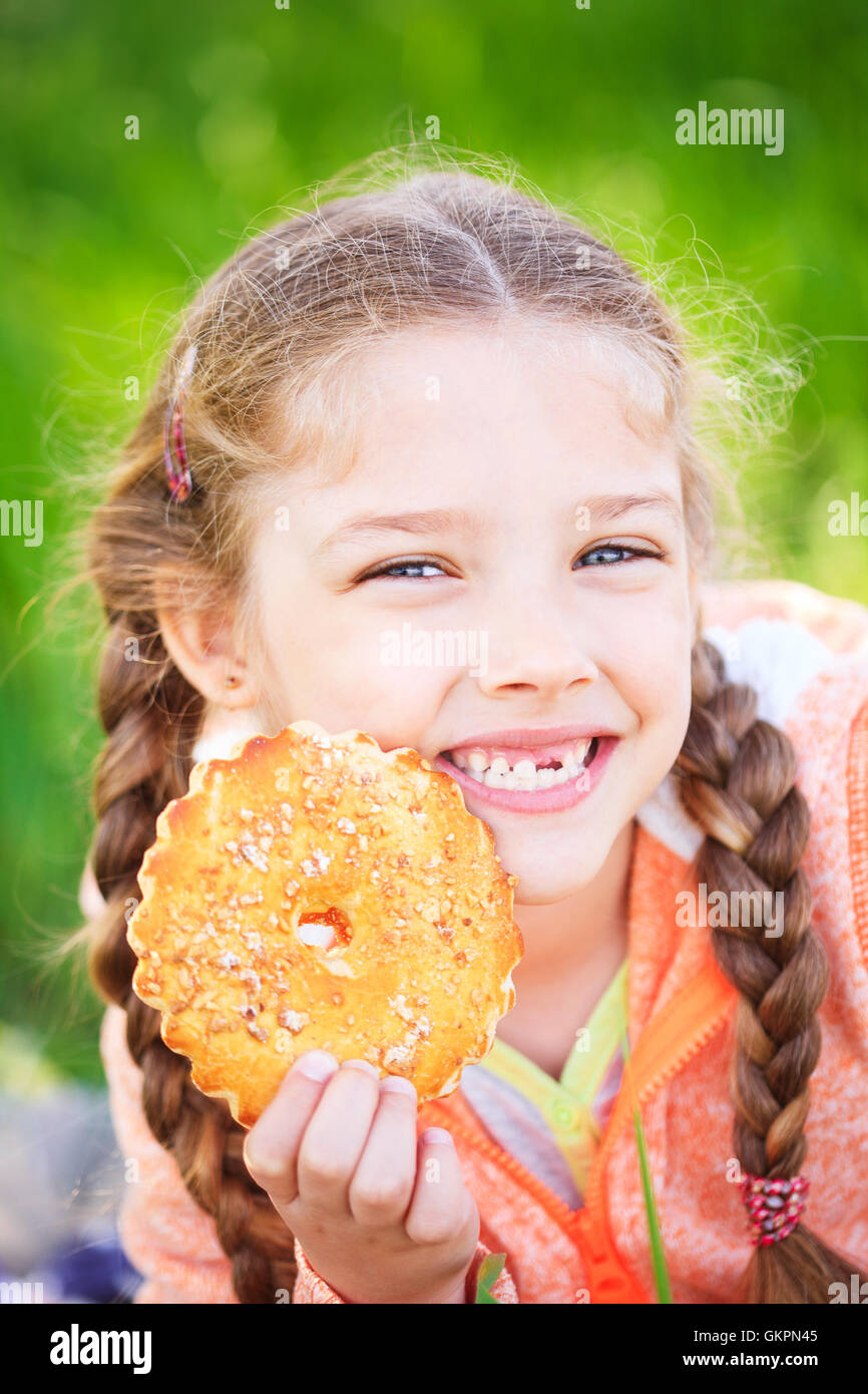 Douce jeune fille tenant un toth holding cookies dans sa main sur la nature Banque D'Images