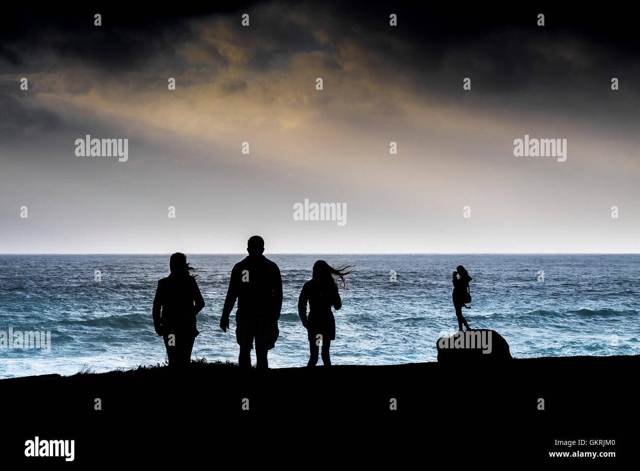 La silhouette de personnes sur un jour de tempête de vent, sur la Pointe à Newquay, Cornwall. Banque D'Images
