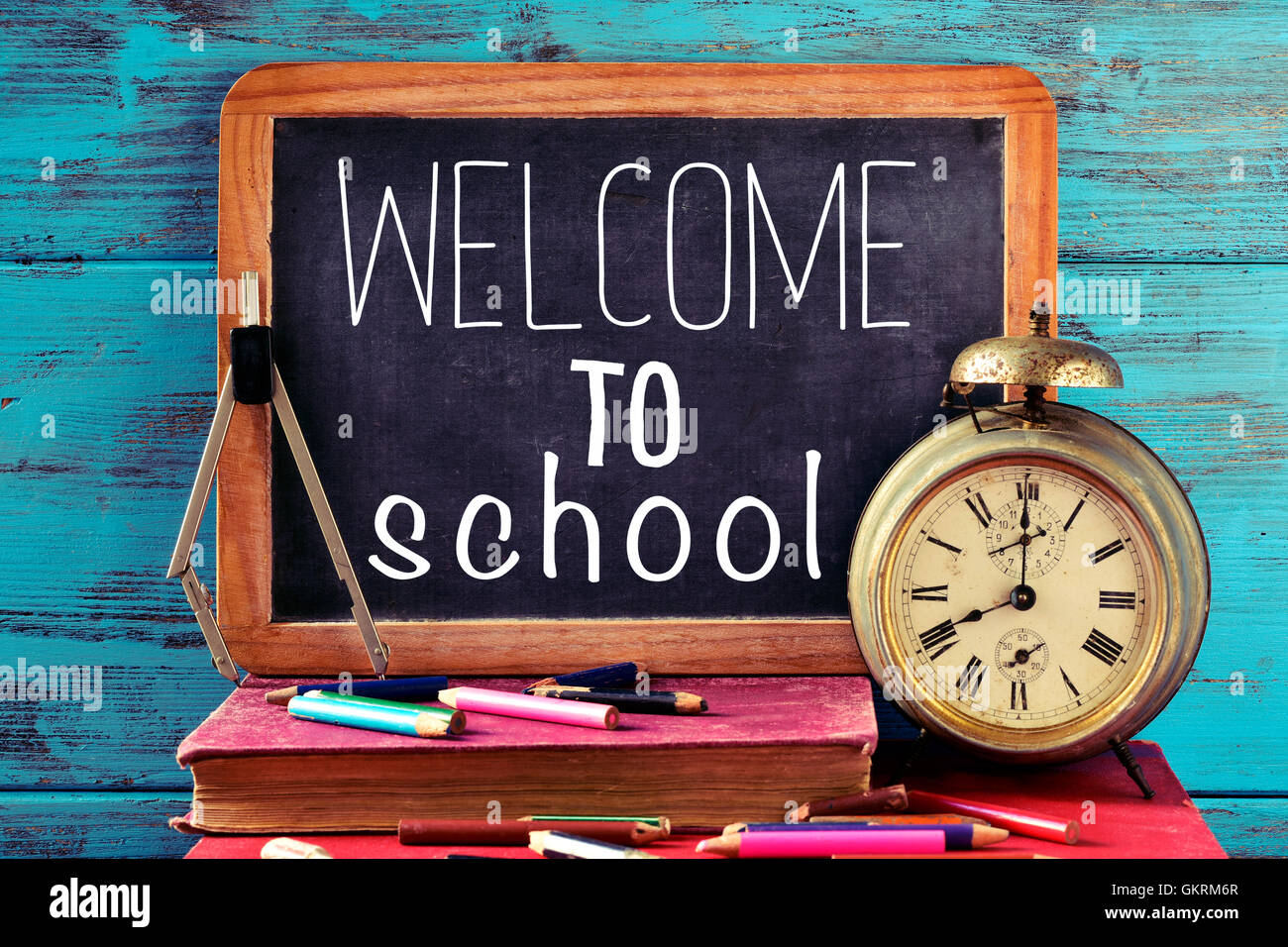 Un tableau sur le texte bienvenue à l'école, certains vieux livres, un vieux réveil, une boussole et quelques crayons de couleur de couleur différente Banque D'Images