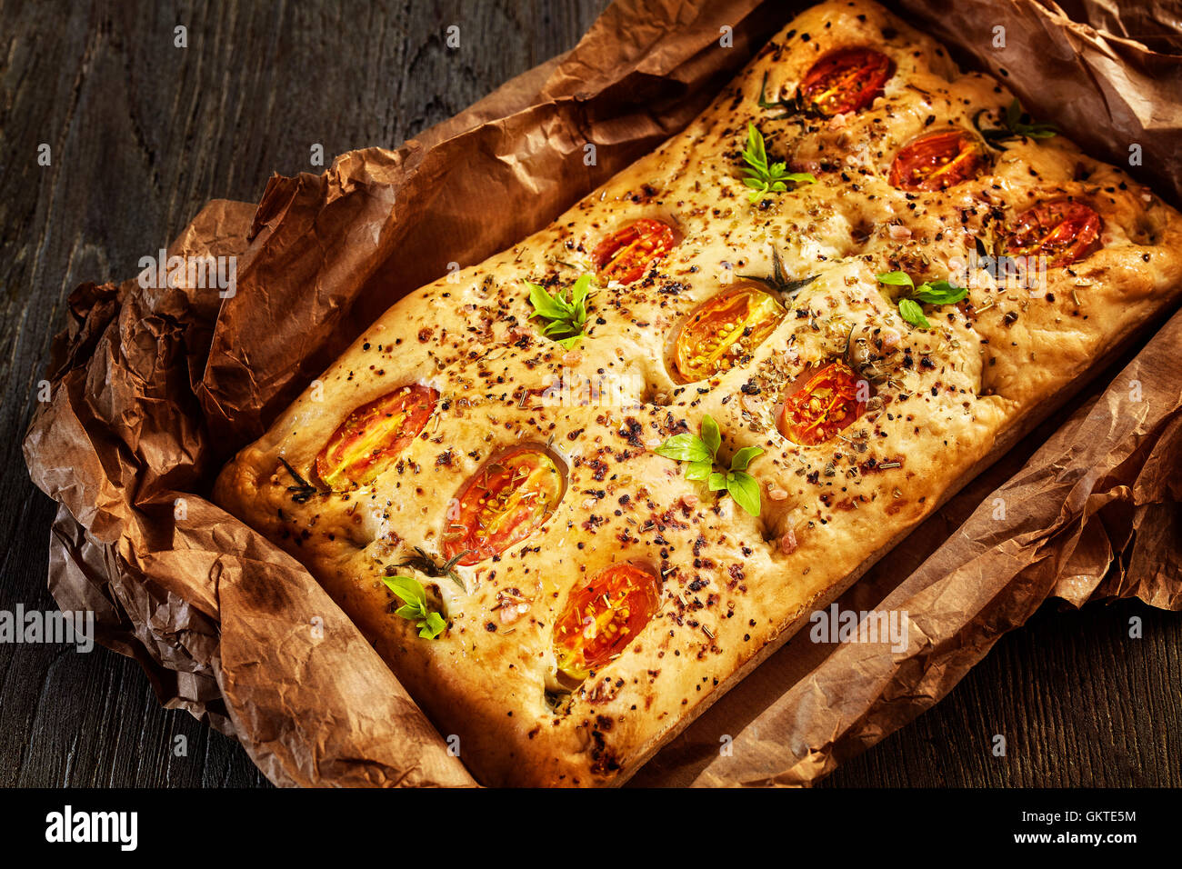 Focaccia italienne fraîchement cuit au four avec des tomates sur une vieille table en bois. Banque D'Images