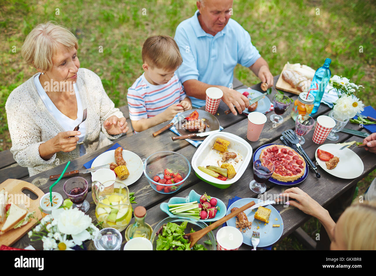 Assis à la table familiale et de manger de la viande grillée avec des légumes en plein air Banque D'Images