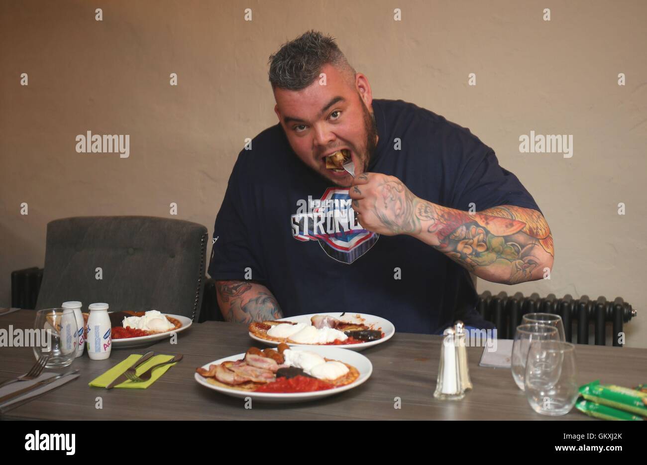 Homme fort irlandais Sean O'Hagan tucks en un petit-déjeuner des champions à Man Vs Food événement à venir de l'Ultime géant homme fort Week-end à la prison de la route, Crumlin à Belfast. Banque D'Images