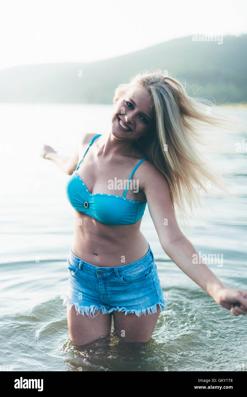 Portraits d'une jeune fille blonde en face d'un lac. Banque D'Images