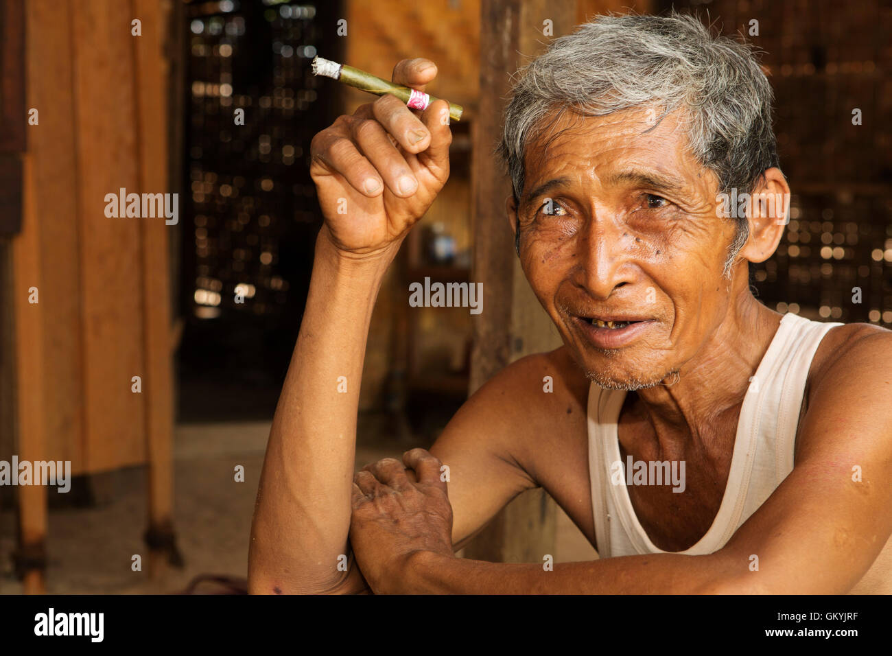 Un homme birman de fumer à sa maison dans Minnathu Village près de Bagan, Myanmar (Birmanie). L'homme fume un cigare roulé à l'échelle locale. Banque D'Images