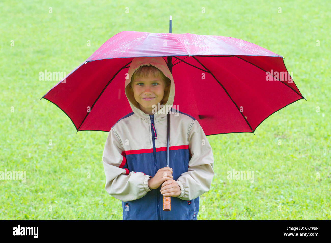 Petit garçon heureux sous parapluie dans la pluie. À l'extérieur. L'enfant  comme temps de pluie Photo Stock - Alamy