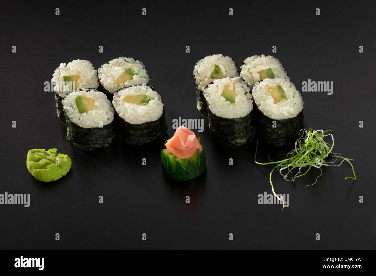 Rouleaux de sushi hosomaki avec avocat décoré de salade d'algues et wasabi Banque D'Images