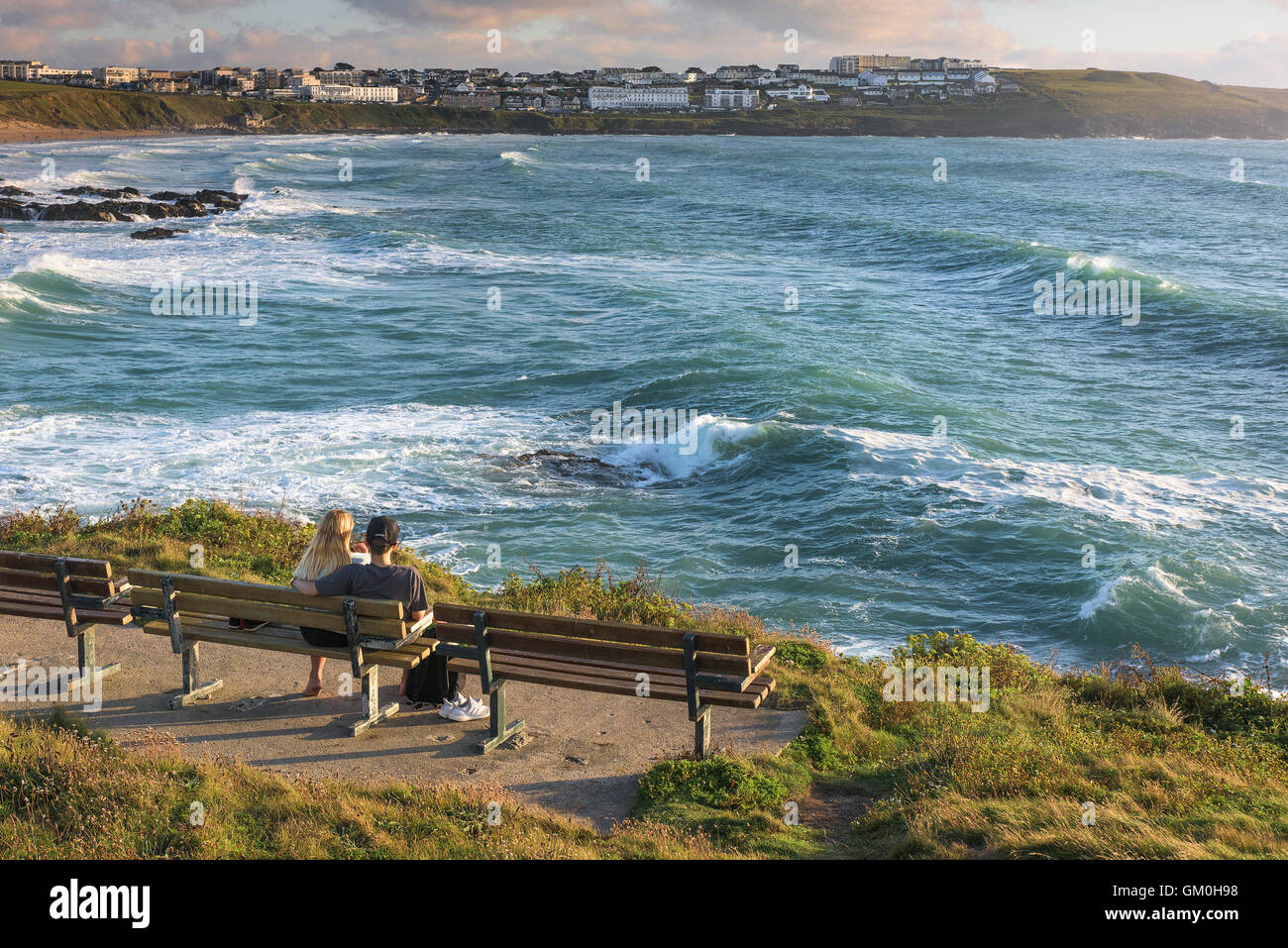 Un jeune couple assis sur un banc, sur la tête de Towan Pointe Towan dominant dans Fistral Newquay, Cornwall. Banque D'Images