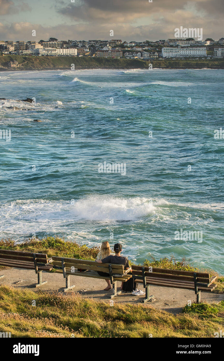Un jeune couple assis sur un banc avec vue sur plage de Towan dans Fistral Newquay, Cornwall. Banque D'Images