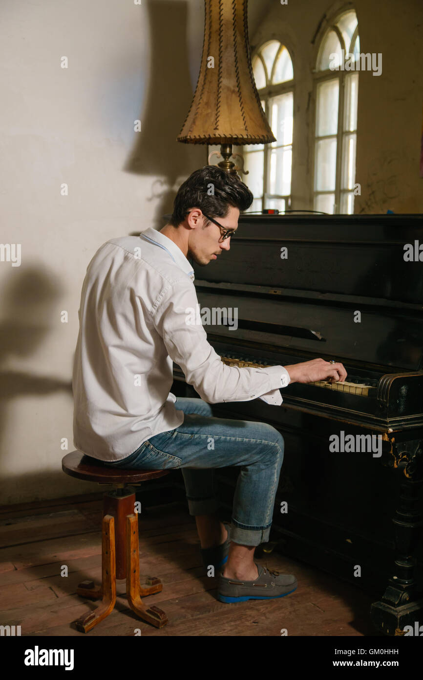 Brun joue du piano assis sur la chaise. Il est inspiré par ce jeu Banque D'Images