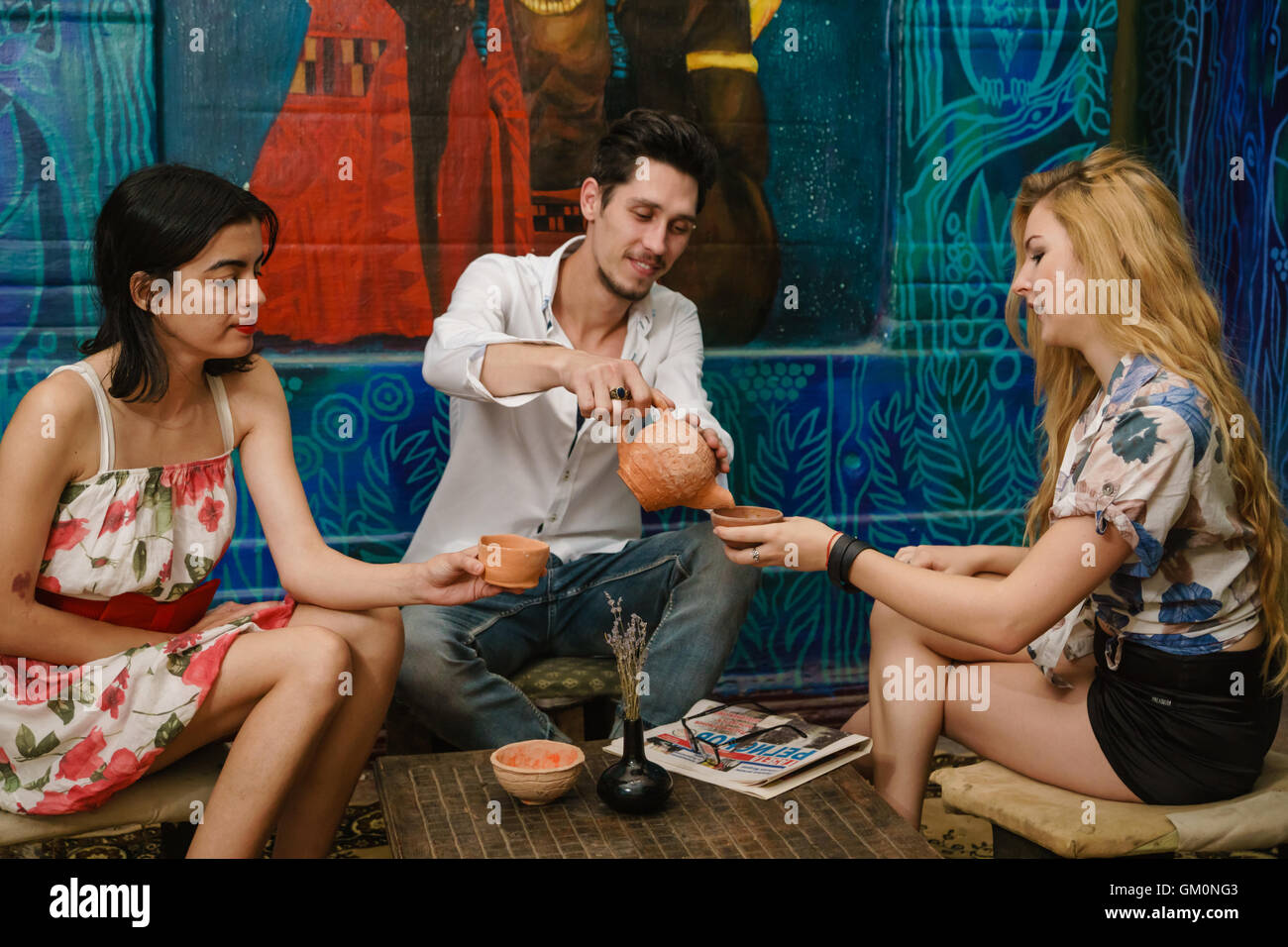 Smiling brunet verse du thé dans la tasse de la blonde et jolie brunette attend pour eux Banque D'Images