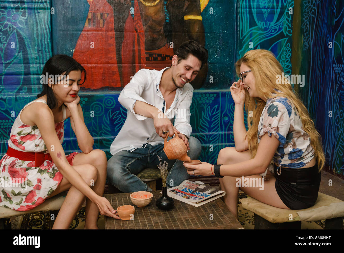 Smiling brunet verse du thé dans la tasse de la blonde et jolie brunette attend pour eux Banque D'Images