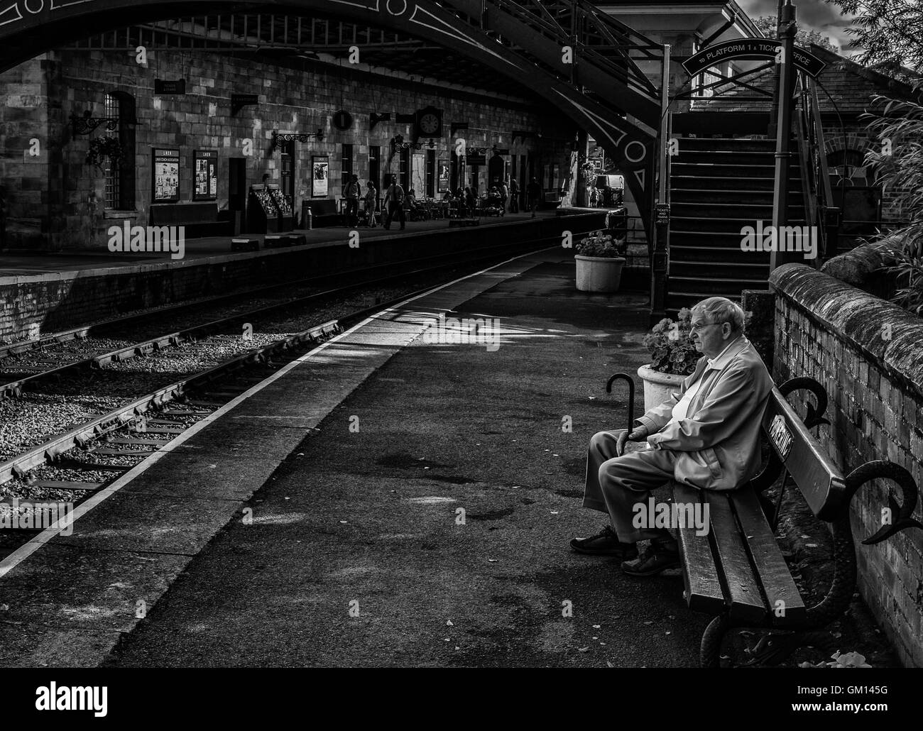 Un homme seul avec ses pensées sur une plate-forme de la gare Banque D'Images