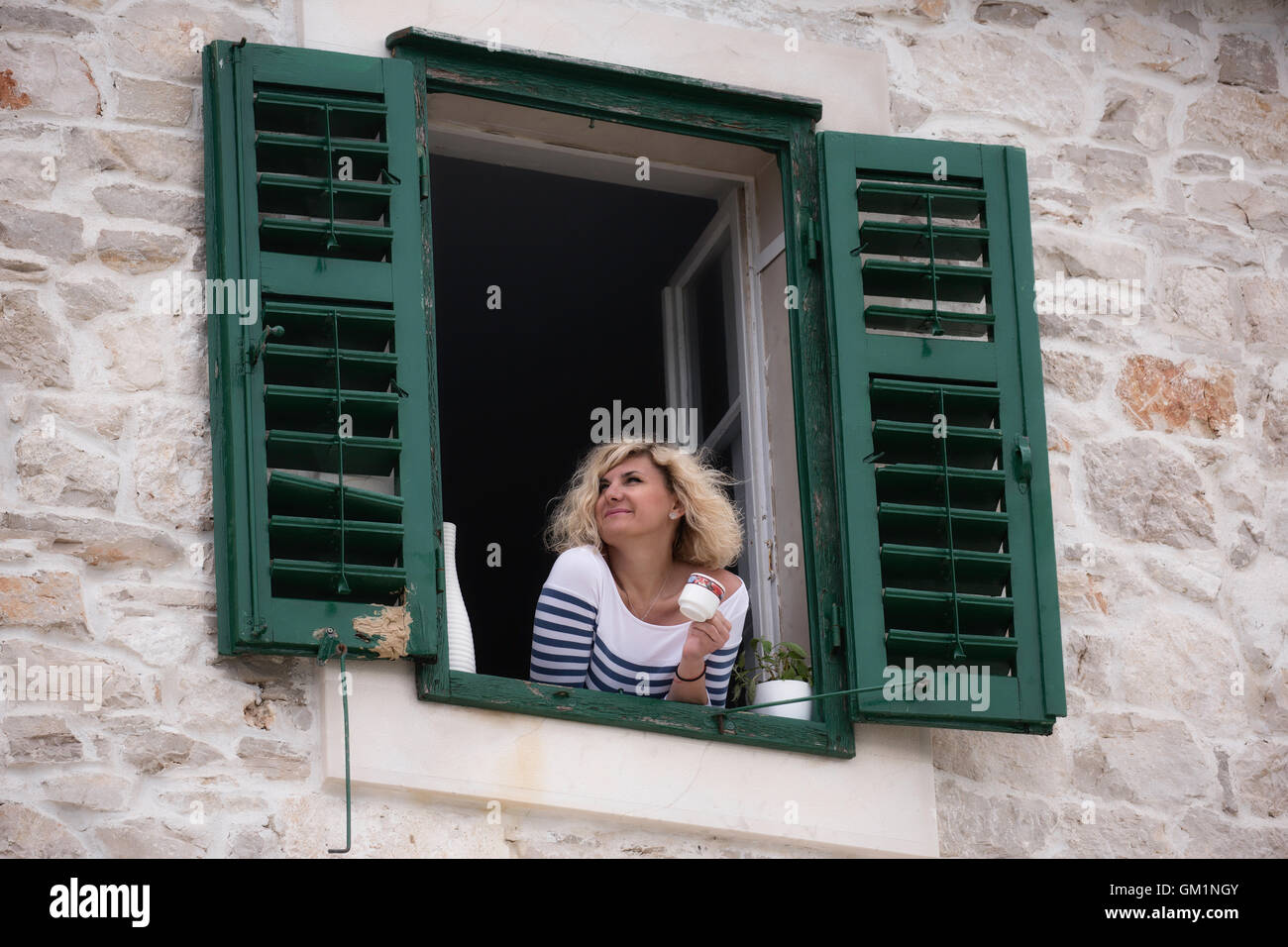 Belle blonde femme est à la recherche dans la distance avec une tasse de café dans ses mains Banque D'Images