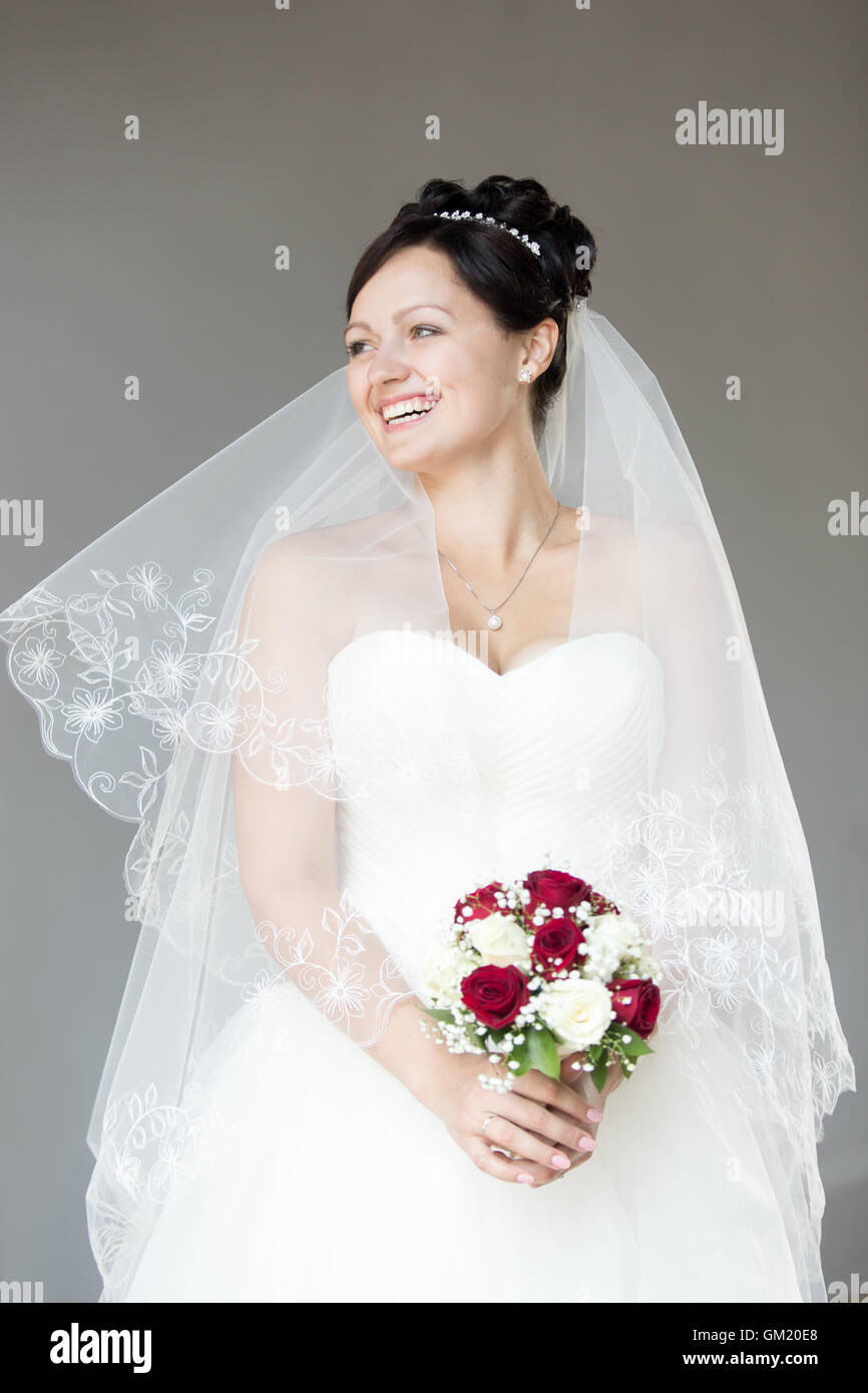 Young happy bride holding bouquet de mariée avec roses blanches et rouges. Belle Mariée avec mariage mode hairstyle Banque D'Images