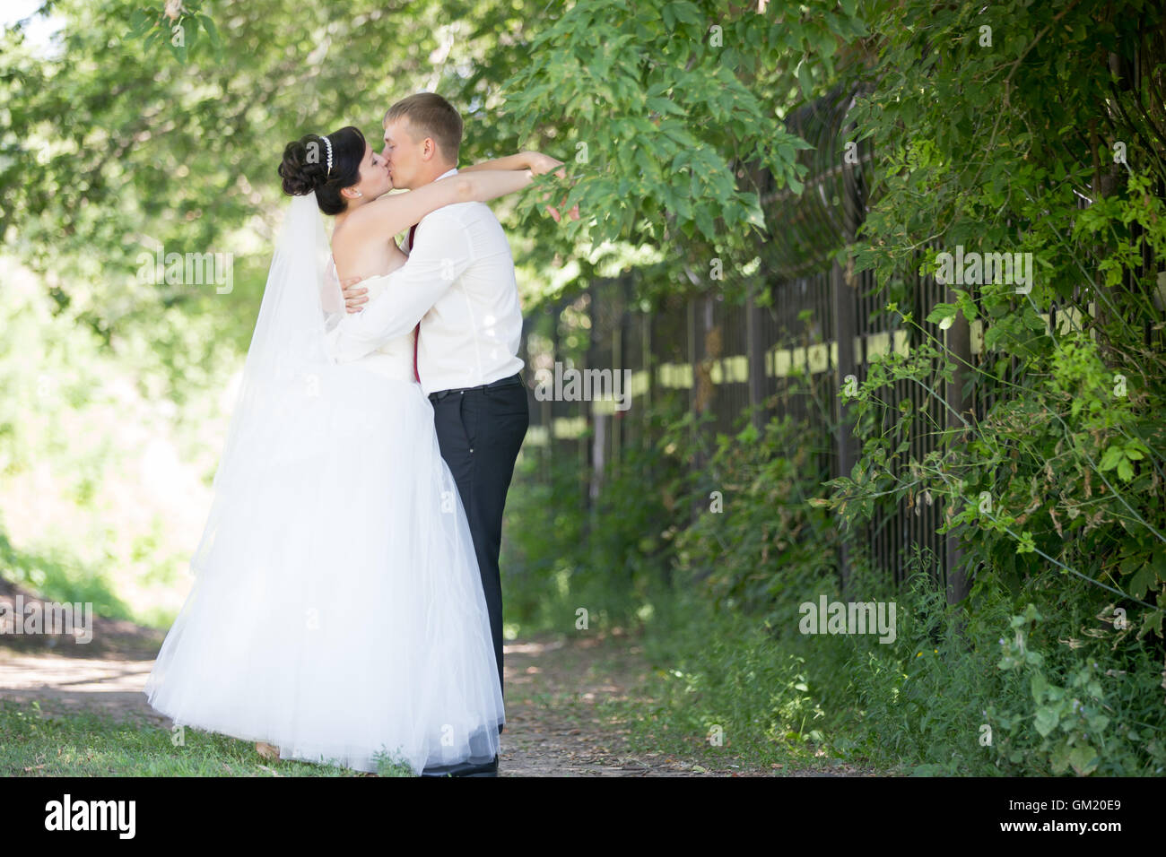 Young Caucasian couple kissing mariage en plein air. Beautiful happy bride embrassant et baisers avec groom sur jour de mariage en été Banque D'Images