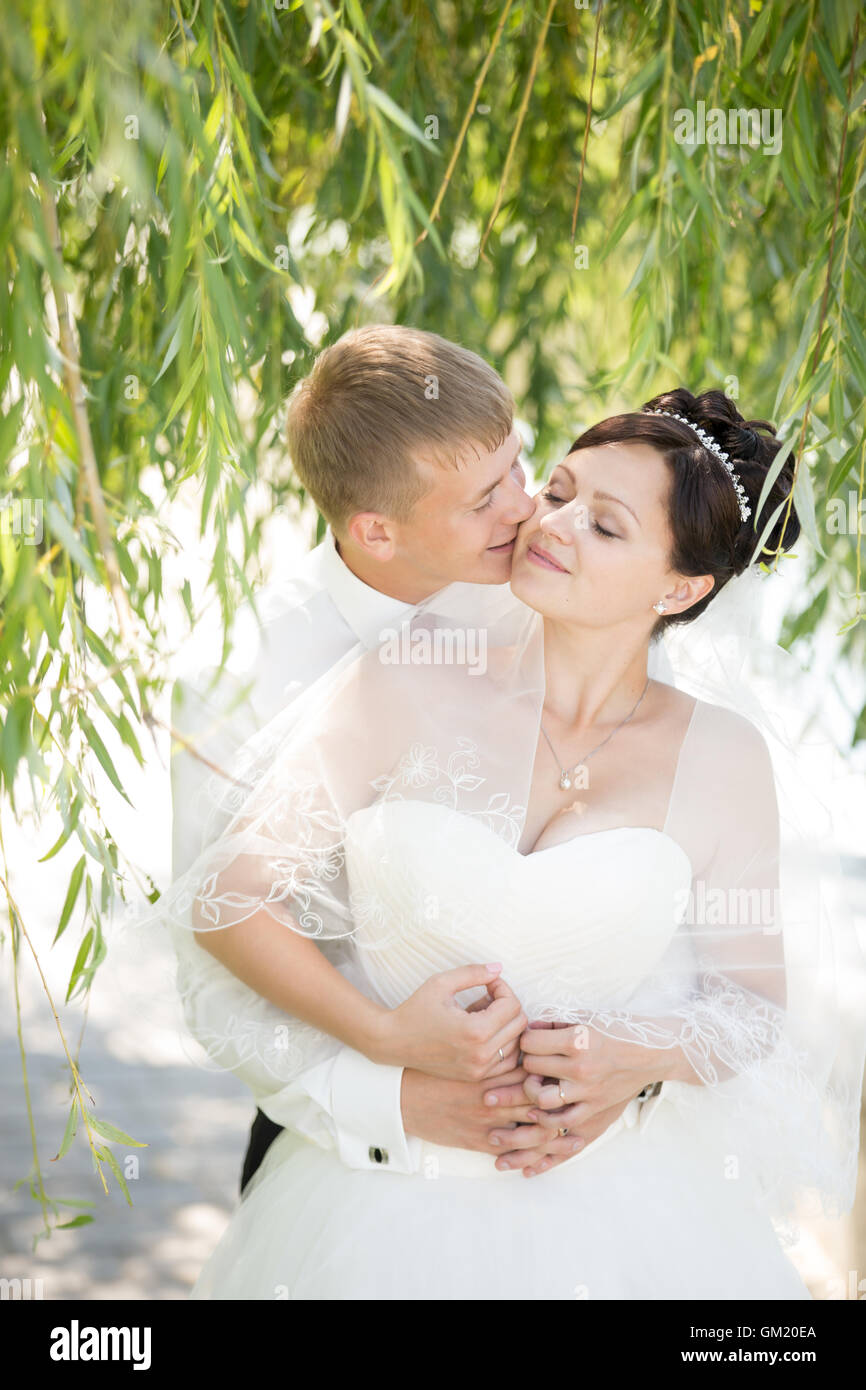 Young Caucasian couple kissing de mariage et profiter du temps ensemble. Faire place au marié et les baisers beautiful happy bride sur le mariage Banque D'Images