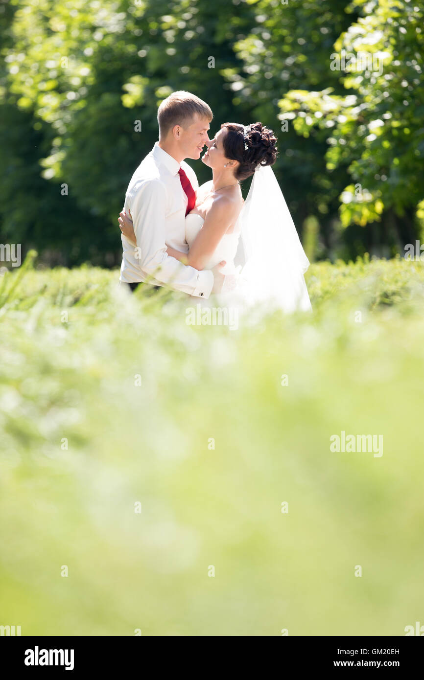 Young Caucasian couple kissing mariage en plein air. Beaux jeunes mariés embrassant et en l'embrassant sur le jour du mariage en été. L'amour Banque D'Images