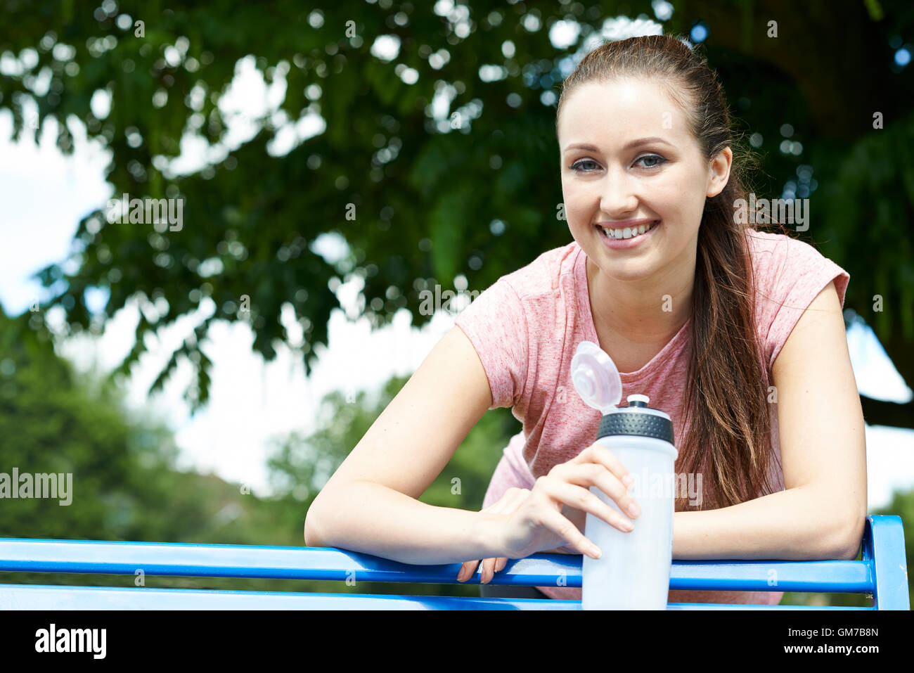 Jeune femme reposant sur banc de parc au cours de l'effort Banque D'Images