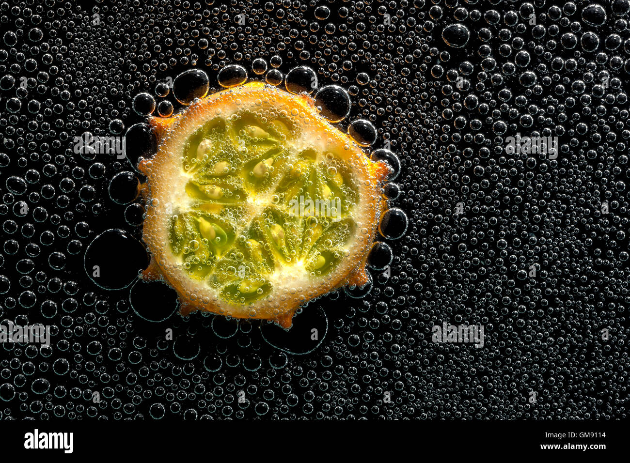 Kiwano fruit melon à cornes, dans l'eau minérale, une série de photos. Close-up de l'eau gazéifiée sur fond noir Banque D'Images
