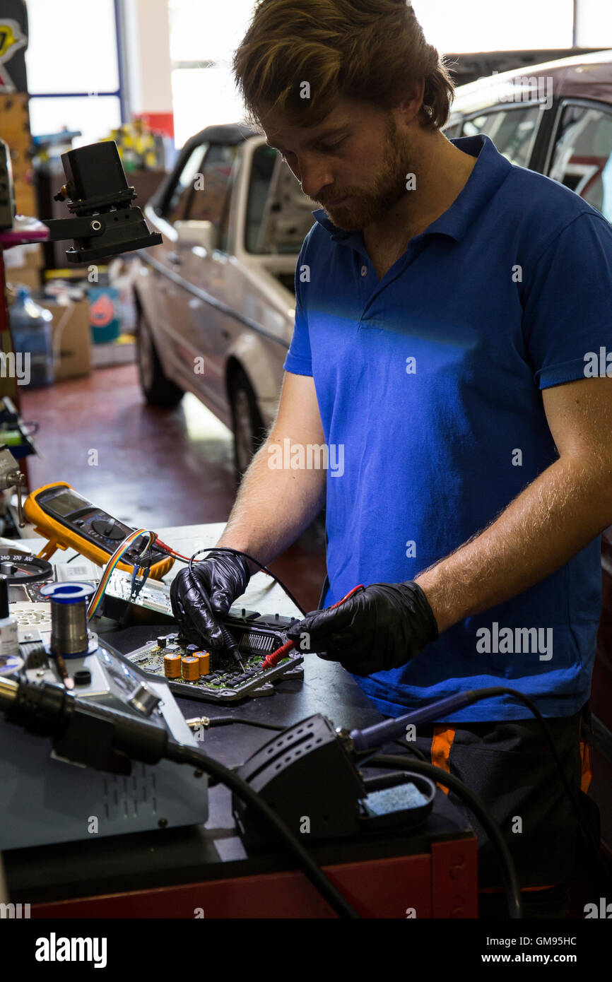 Une fixation mécanique de pièces de voiture électronique dans son atelier Banque D'Images