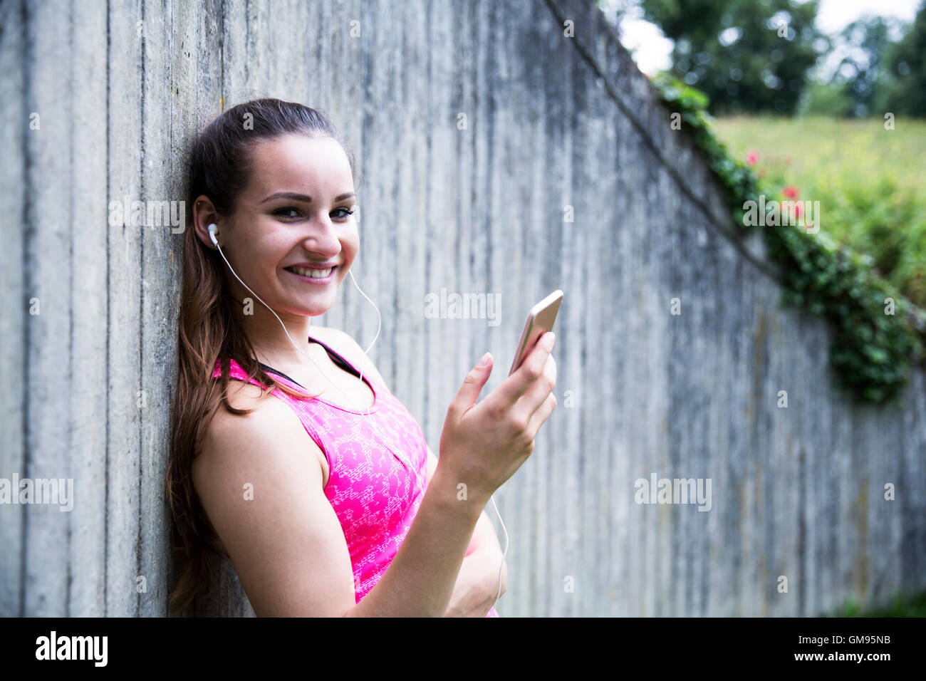 Jeune femme sportive avec le smartphone et écouteurs Banque D'Images