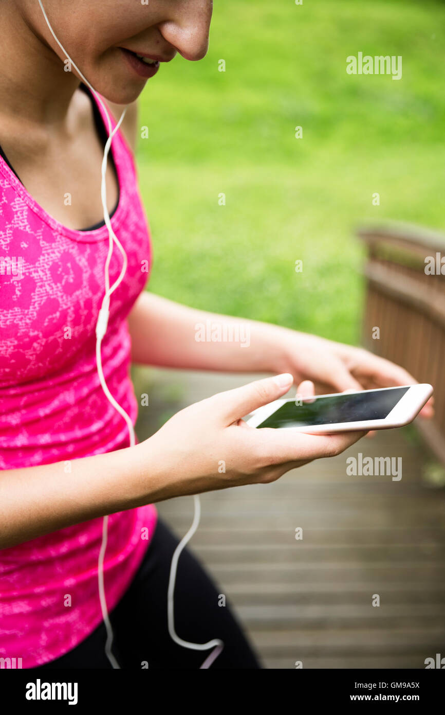 Jeune femme sportive avec le smartphone et écouteurs Banque D'Images