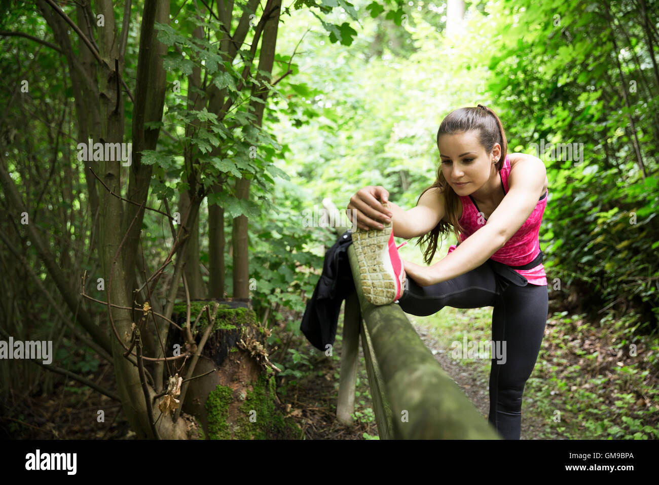 Jeune femme sportive qui s'étend dans la forêt Banque D'Images