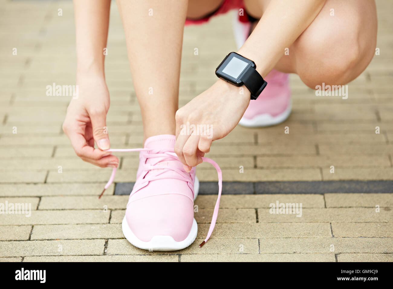 Jeune femme runner avec appareil de fitness portable lacet de liage, close-up. Banque D'Images