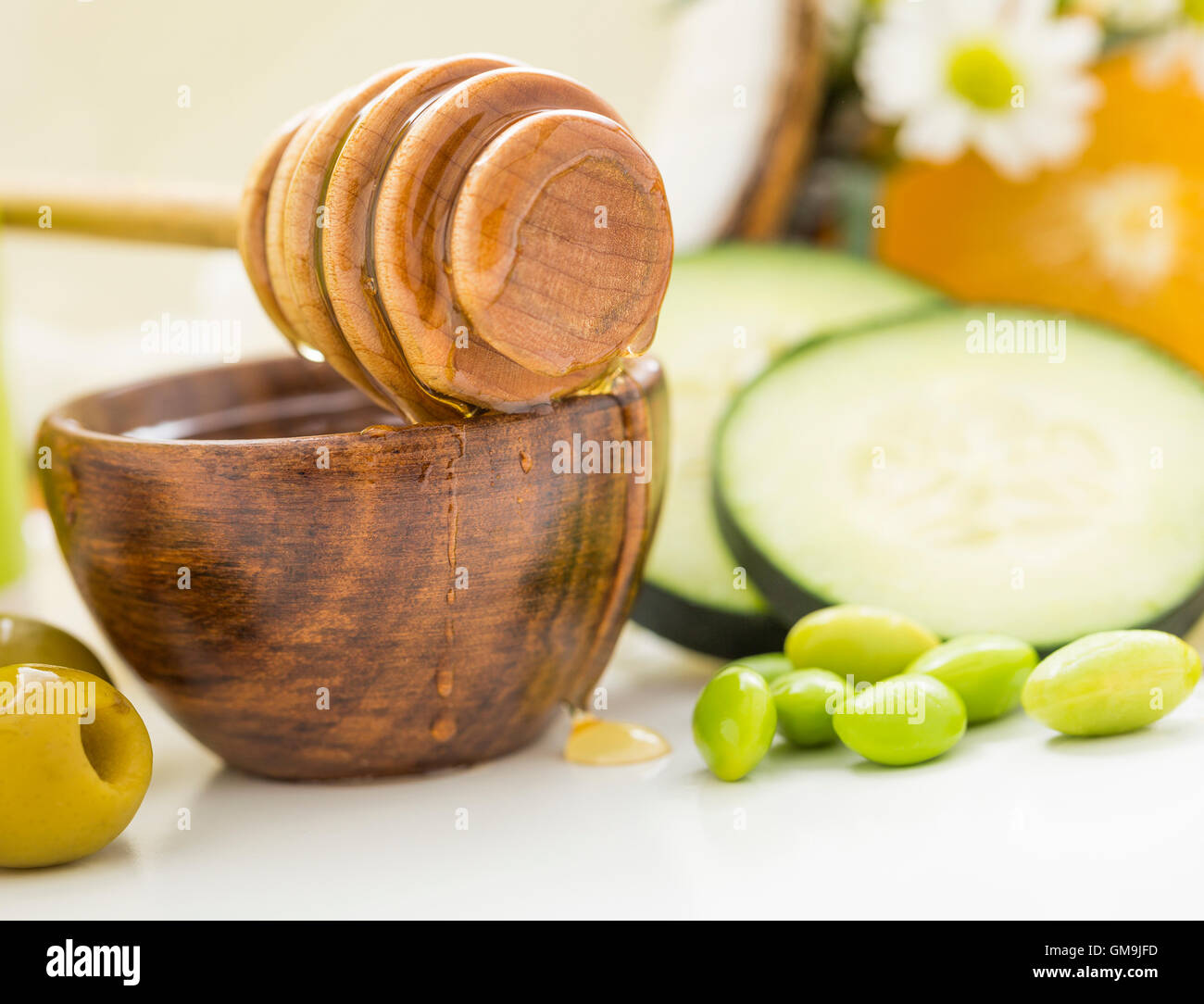 Le miel balancier sur bol, olives, petits pois et des tranches de concombre Banque D'Images