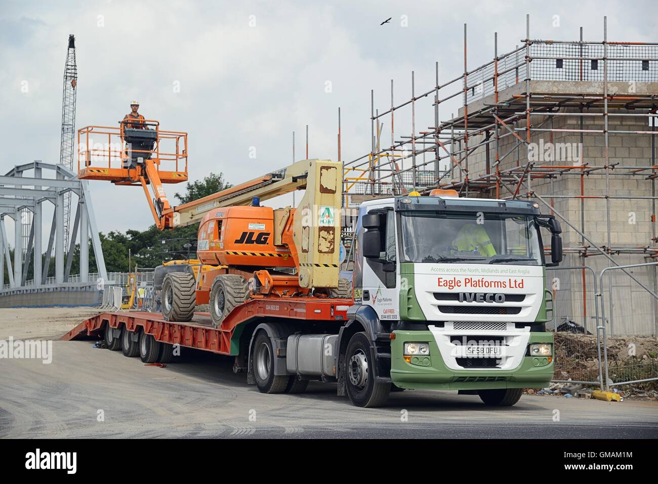 Un ouvrier rives une grue sur un camion Iveco remorque chargeur faible et administré par Eagle plates-formes sur un chantier de construction Banque D'Images