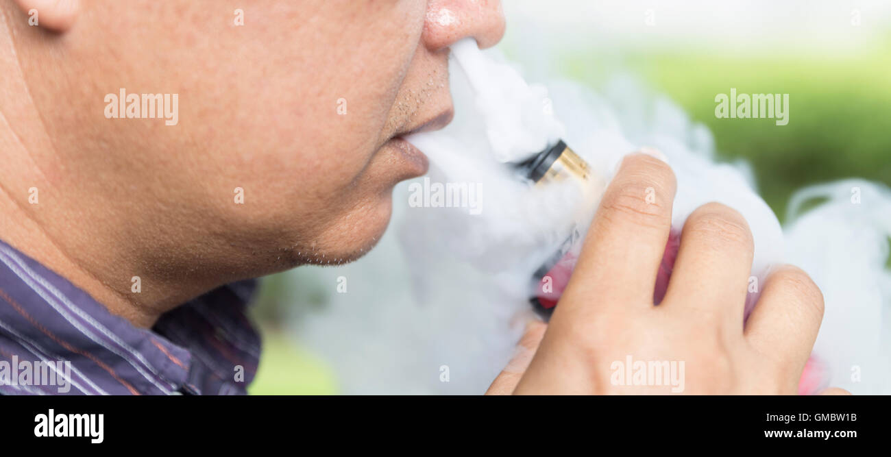 Man blowing fumée de cigarette électronique de sa bouche et nez Banque D'Images
