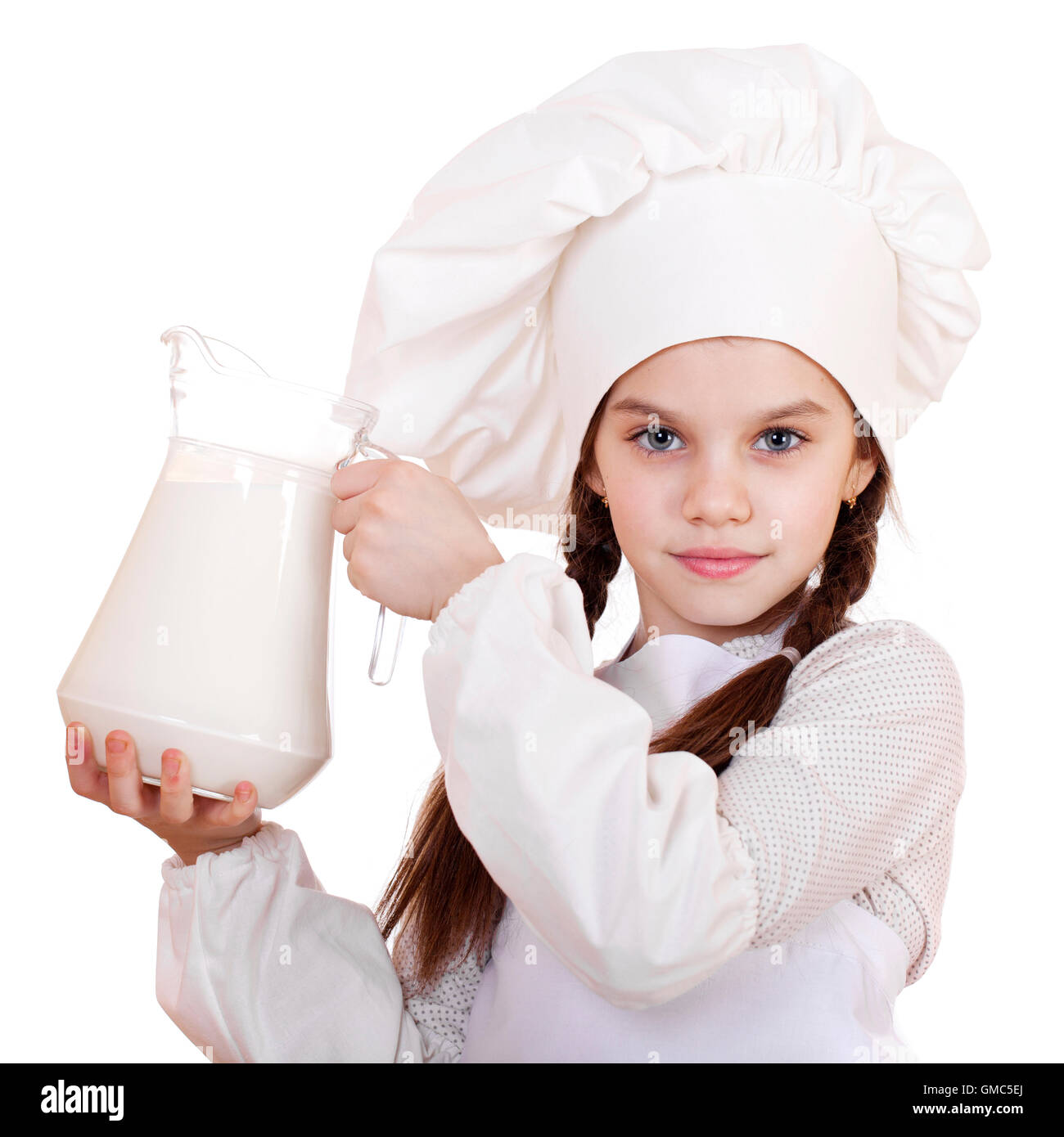 La cuisine et les gens concept - petite fille dans un tablier blanc tenant une cruche de lait, isolé sur fond blanc Banque D'Images