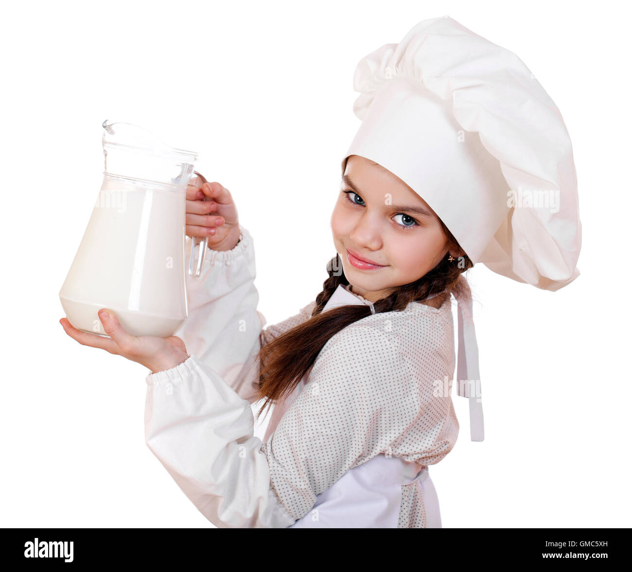 La cuisine et les gens concept - petite fille dans un tablier blanc tenant une cruche de lait, isolé sur fond blanc Banque D'Images