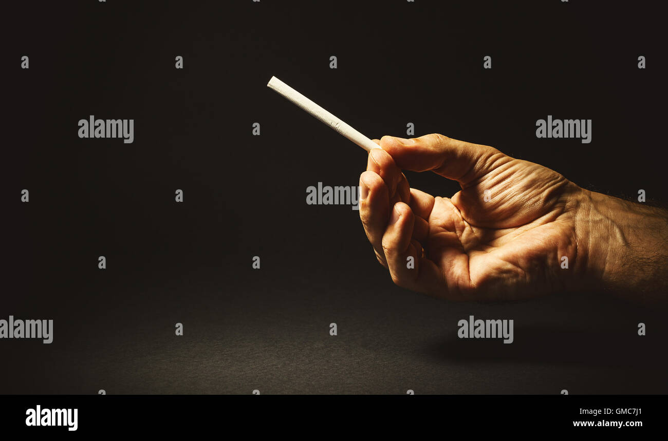 Composition conceptuelle sur le tabagisme, studio shot de la main d'un homme tenant un cigare. Banque D'Images
