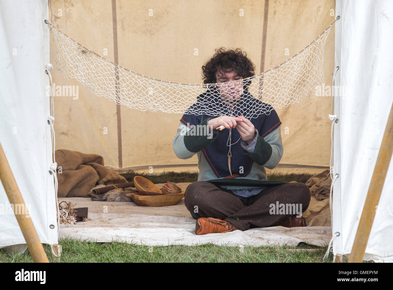 Guerre civile anglaise reenactor royaliste réparant un filet dans un campement. Spetchley Park, Worcestershire, Angleterre. Banque D'Images