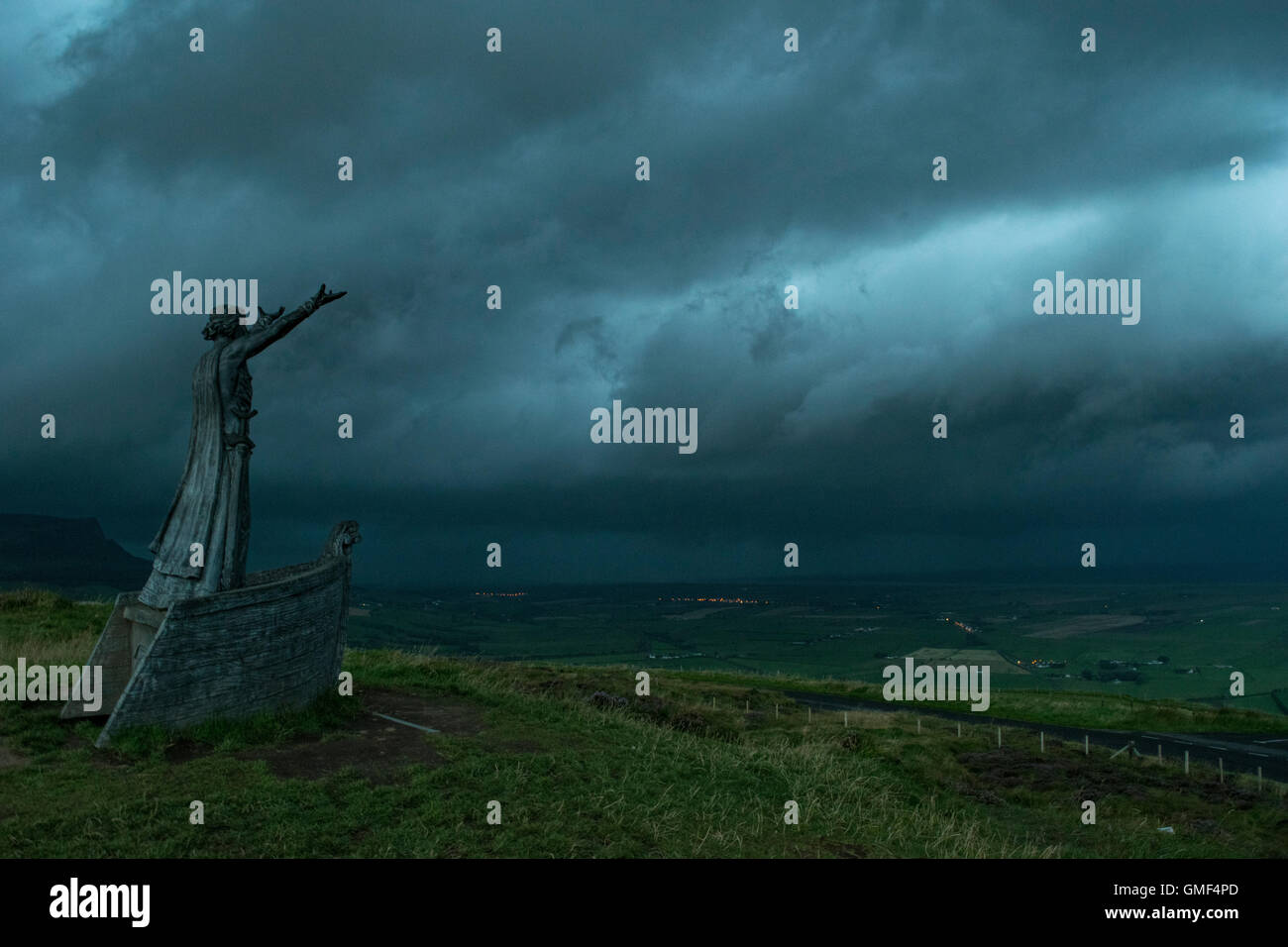Limavady, le comté de Londonderry, Royaume-Uni, 25/08/2016 La statue de Mananna Mac Lir, un dieu de la mer Celtique, se dresse l'oeil sur la montagne Binevenagh qu'une cellule orageuse se déplace jusqu'à Lough Foyle et le long de la côte nord, ce qui porte le tonnerre, les éclairs et la pluie torrentielle avec Crédit : Eoin McConnell/Alamy Live News Banque D'Images