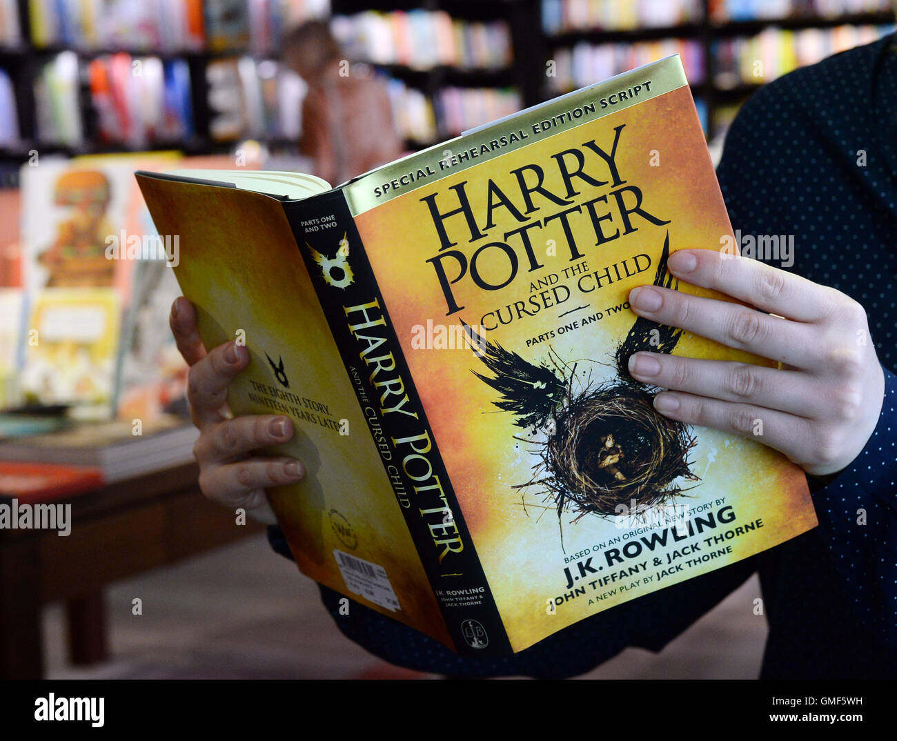 Berlin, Allemagne. Août 25, 2016. ILLUSTRATION - Une femme détient le livre "Harry Potter et l'enfant maudit, Parties I et II' de Joanne K. Rowling dans ses mains dans le 'English Bookshop" de la culture department store Dussmann à Berlin, Allemagne, 25 août 2016. Le script d'une pièce sur le dessus de la liste des best-sellers ? Et, en plus, un en anglais ? La nouvelle aventure de Harry Potter rend cela possible et faites-le au dessus de la liste des best-sellers pour la troisième fois consécutive. Photo : Jens Kalaene/dpa/Alamy Live News Banque D'Images