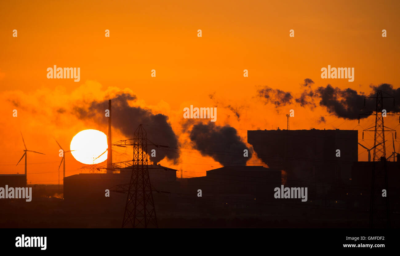 Le soleil se lève derrière la centrale nucléaire de Hartlepool (droite) au lever du soleil. Parc éolien offshore de Teesside au Royaume-Uni en arrière-plan. Banque D'Images