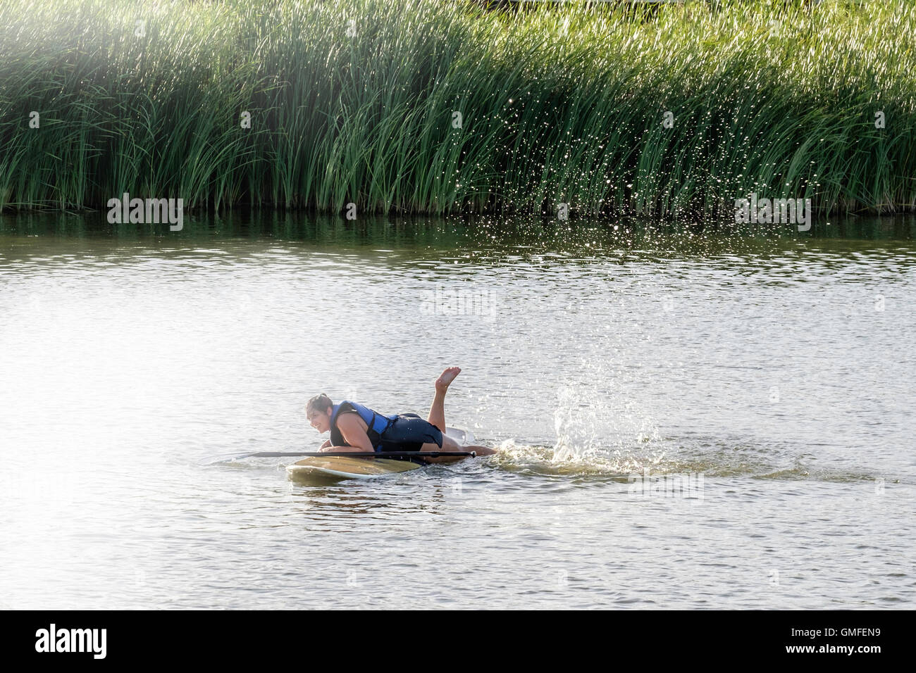 Une femme de race blanche dans son 30s'efforce de revenir sur son paddle board après tomber dans une rivière. New York, USA. Banque D'Images