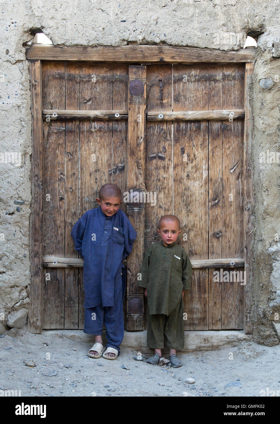 De jeunes Afghans avec le crâne rasé, debout devant une porte en bois, la province de Badakhshan, Afghanistan, Khandood Banque D'Images