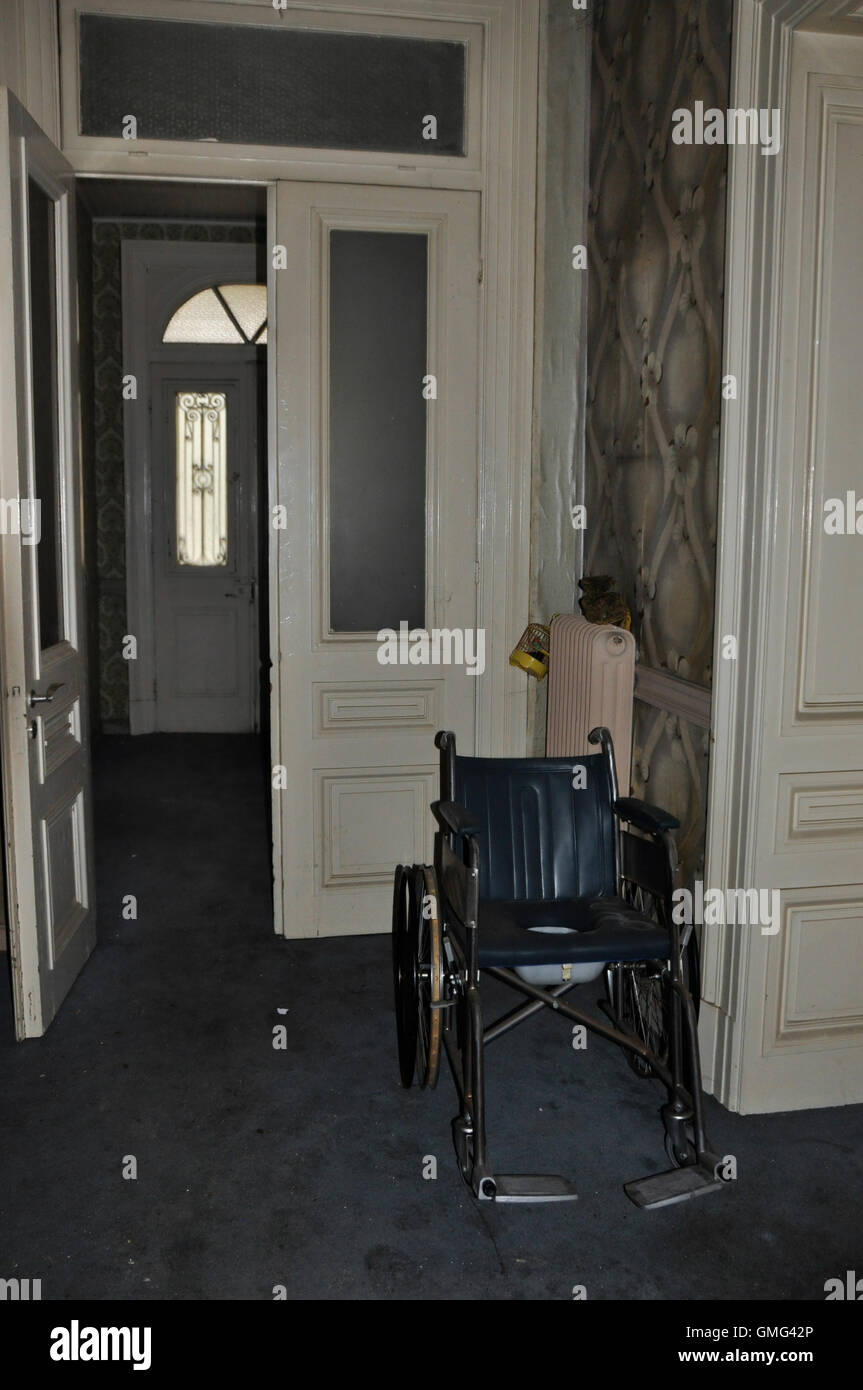 Vintage fauteuil roulant et portes en verre maison abandonnée. Banque D'Images