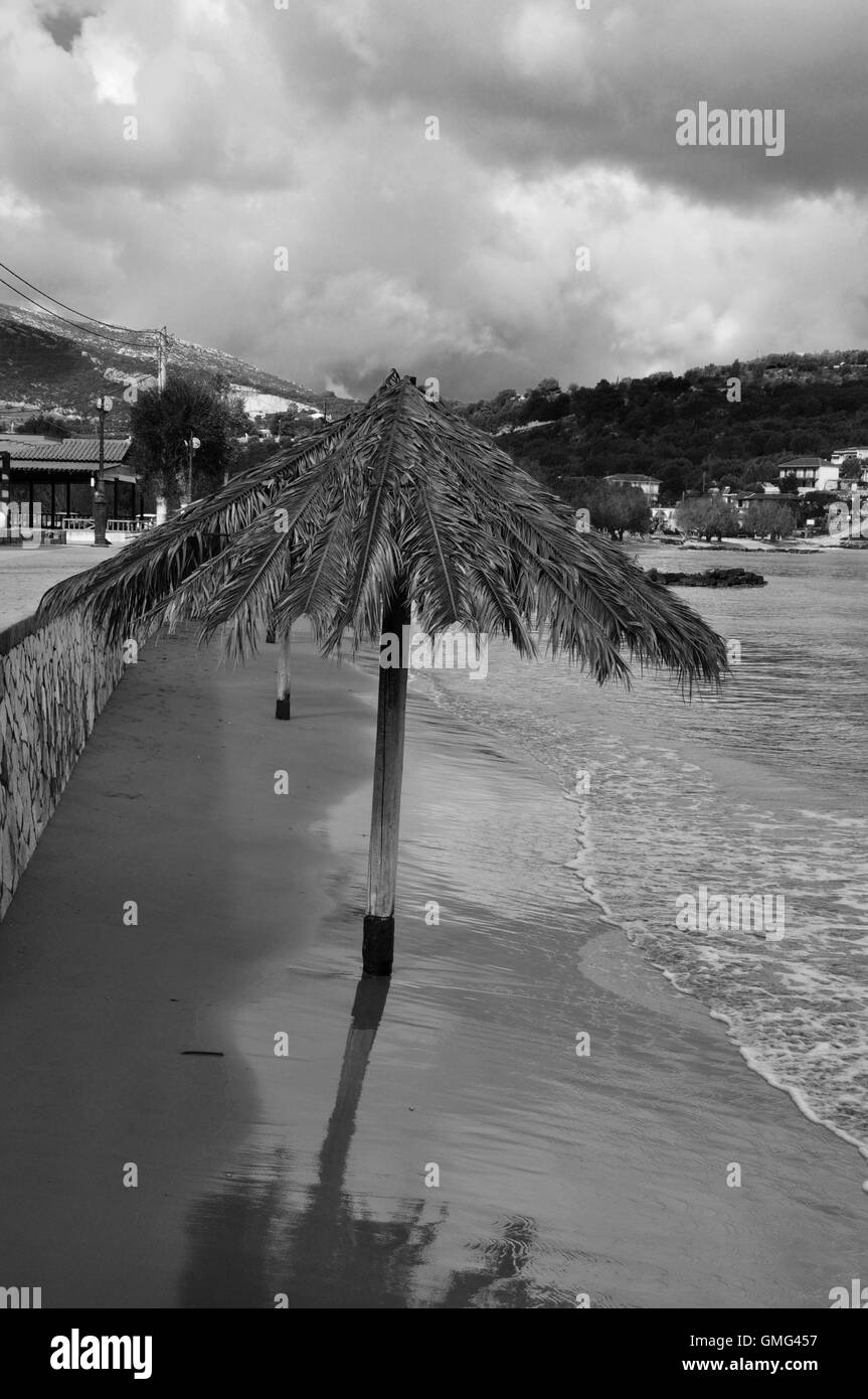 Plage de sable en hiver et parasol avec feuilles de palmier. Noir et blanc. Banque D'Images