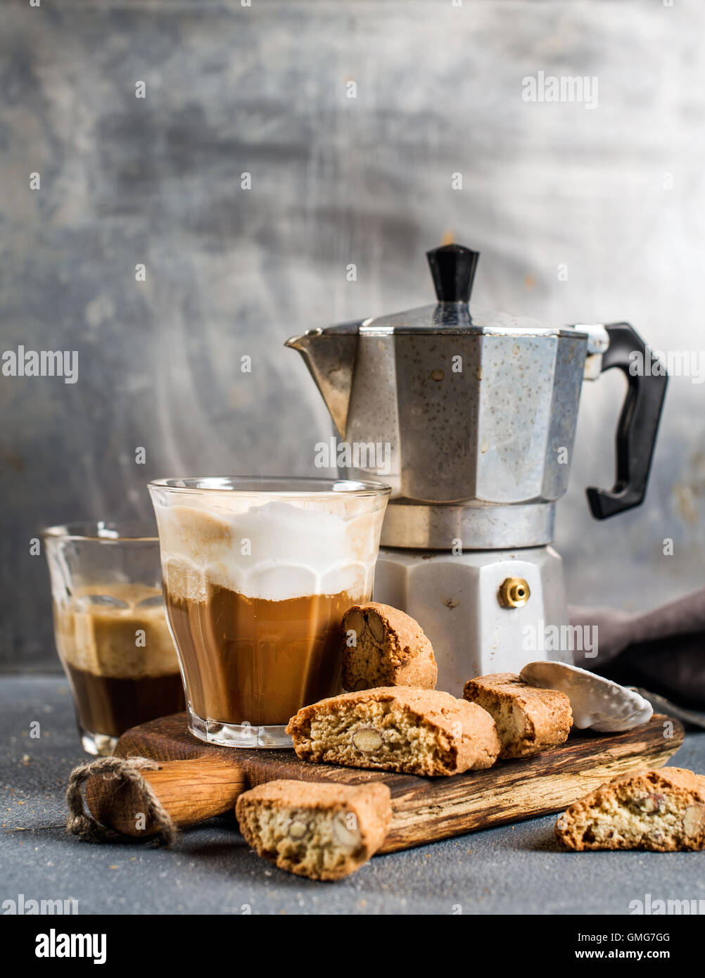 Verre de café latte en bois rustique, conseil sur les cantucci biscuit et de l'acier Moka italienne pot, fond gris Banque D'Images