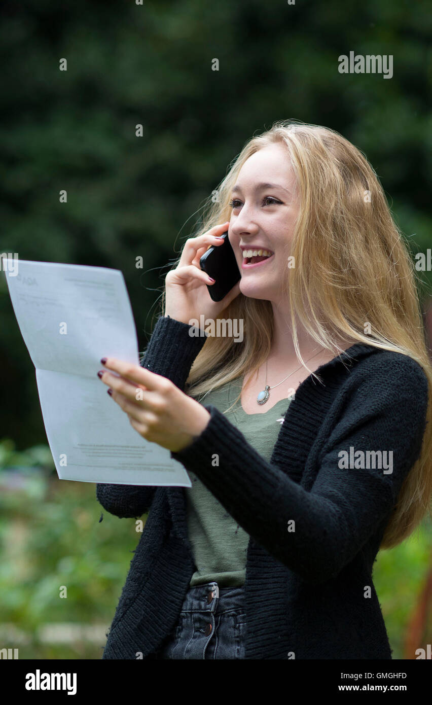 Une bonne élève GCSE fille sur le téléphone après avoir reçu son GCSE résultats. Banque D'Images