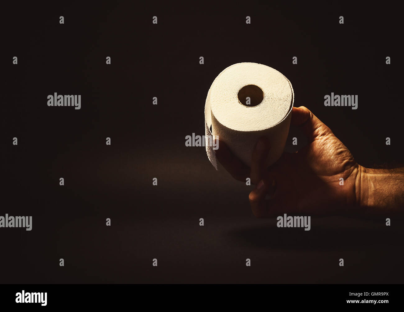 Composition conceptuelle, man's hand holding ou de donner un rouleau de papier de toilette. Banque D'Images