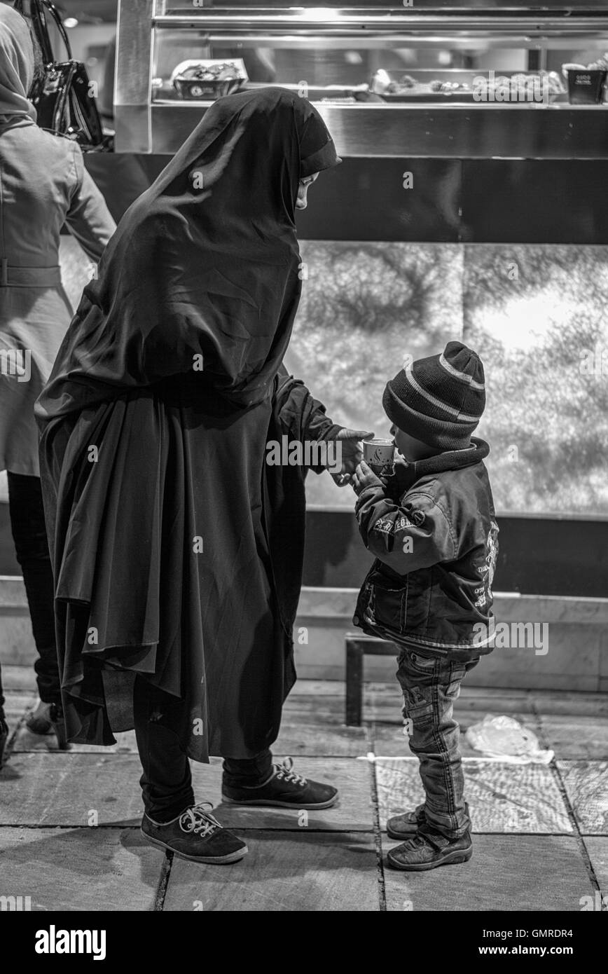 Mère en tchador aidant son fils boire du jus de carotte à partir d'une position sur la rue à Isfahan, Iran. Banque D'Images