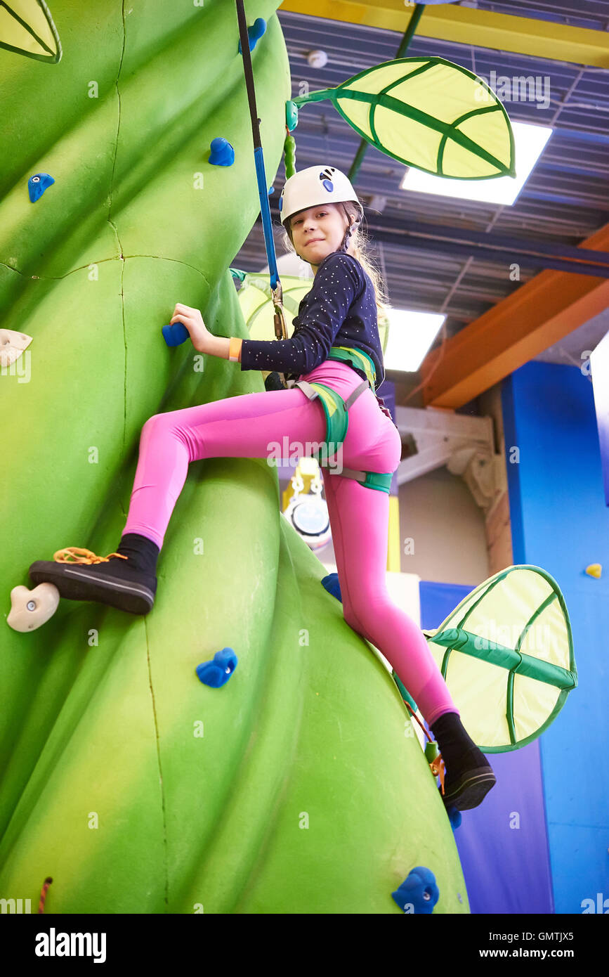 Girl climbing au parc d''à green tree Banque D'Images