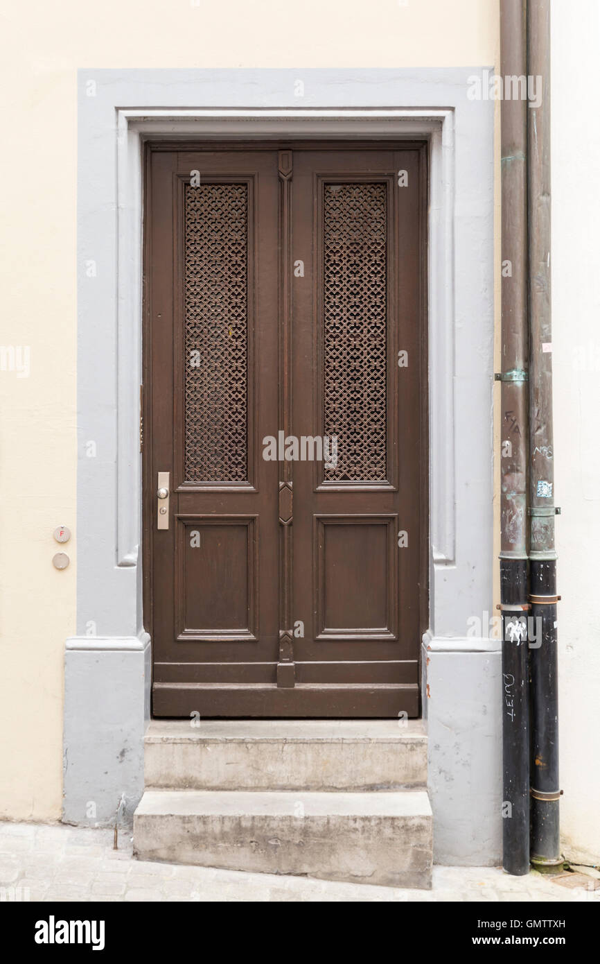 Une porte avec cadre gris brun, mur de couleur crème et la pluie tuyaux sur le côté droit. Banque D'Images