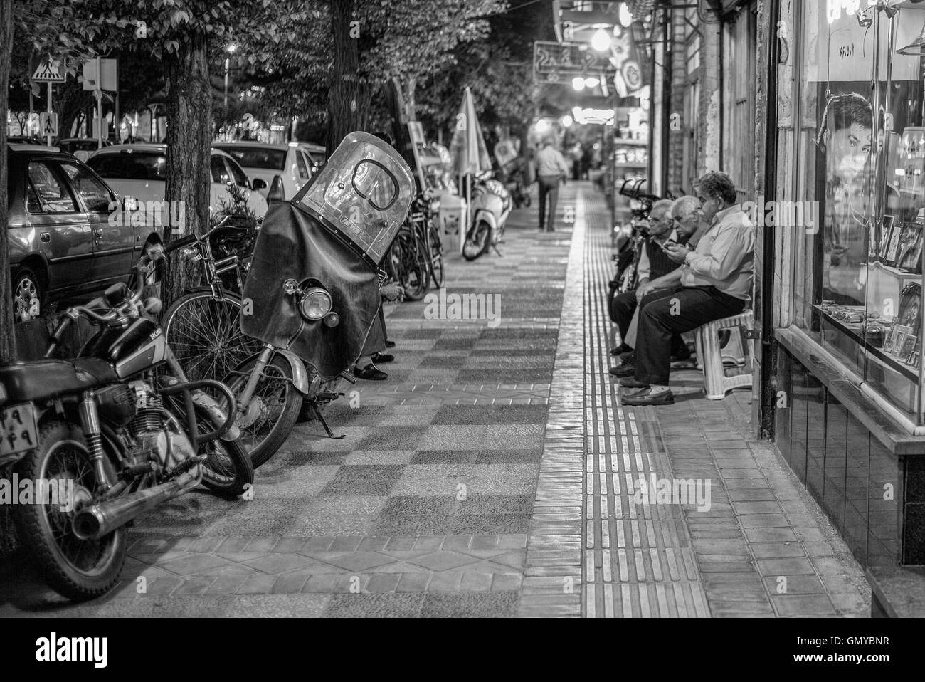 Les hommes assis à l'extérieur d'une boutique sur la rue à Yazd, Iran, la nuit. Banque D'Images