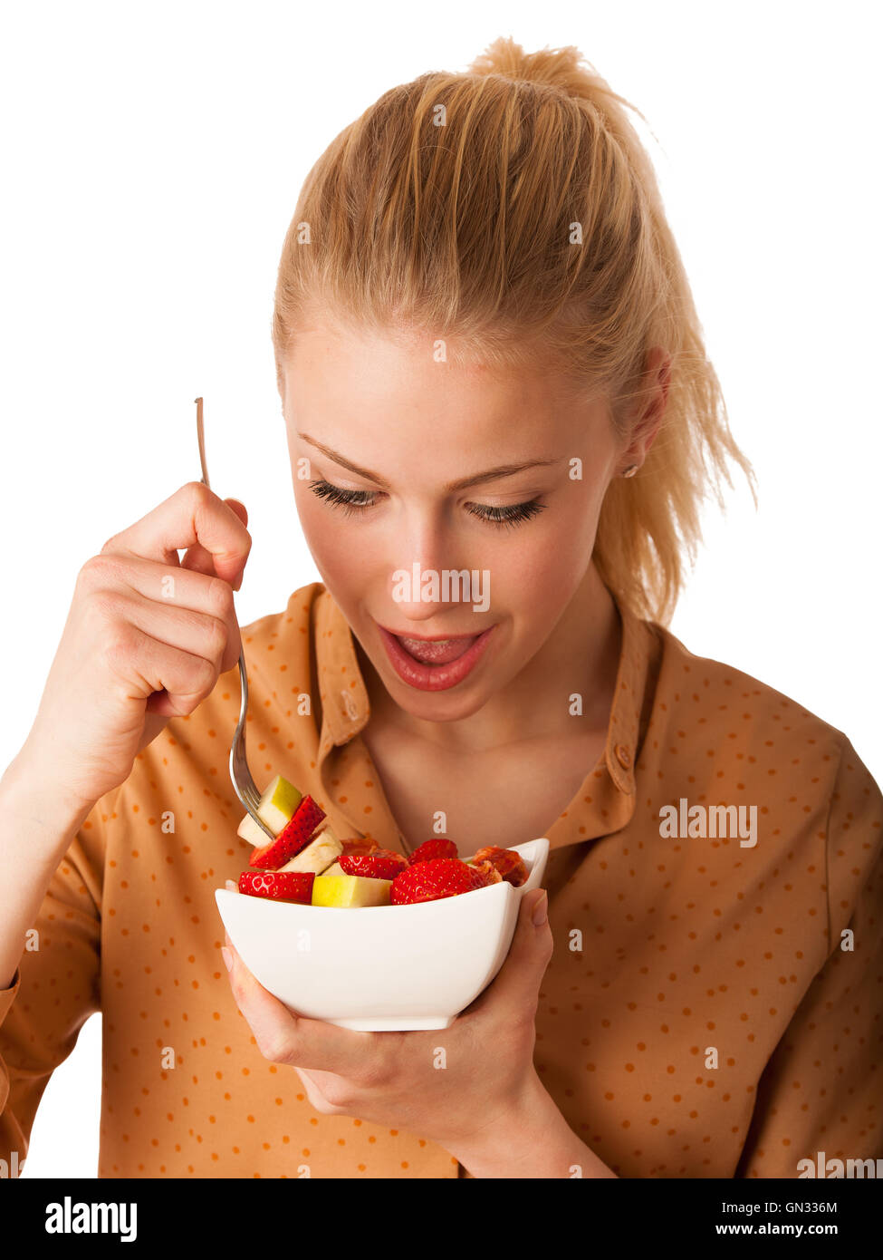 Très belle jeune femme blonde caucasienne est titulaire d'une délicieuse salade de fruits comme un signe de saine alimentation isolé sur fond blanc Banque D'Images